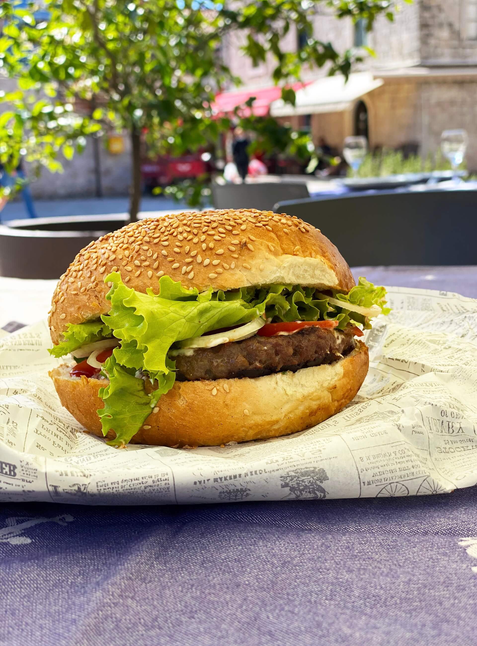 L'hamburger Baća su un panino al sesamo, avvolto in carta da giornale.
